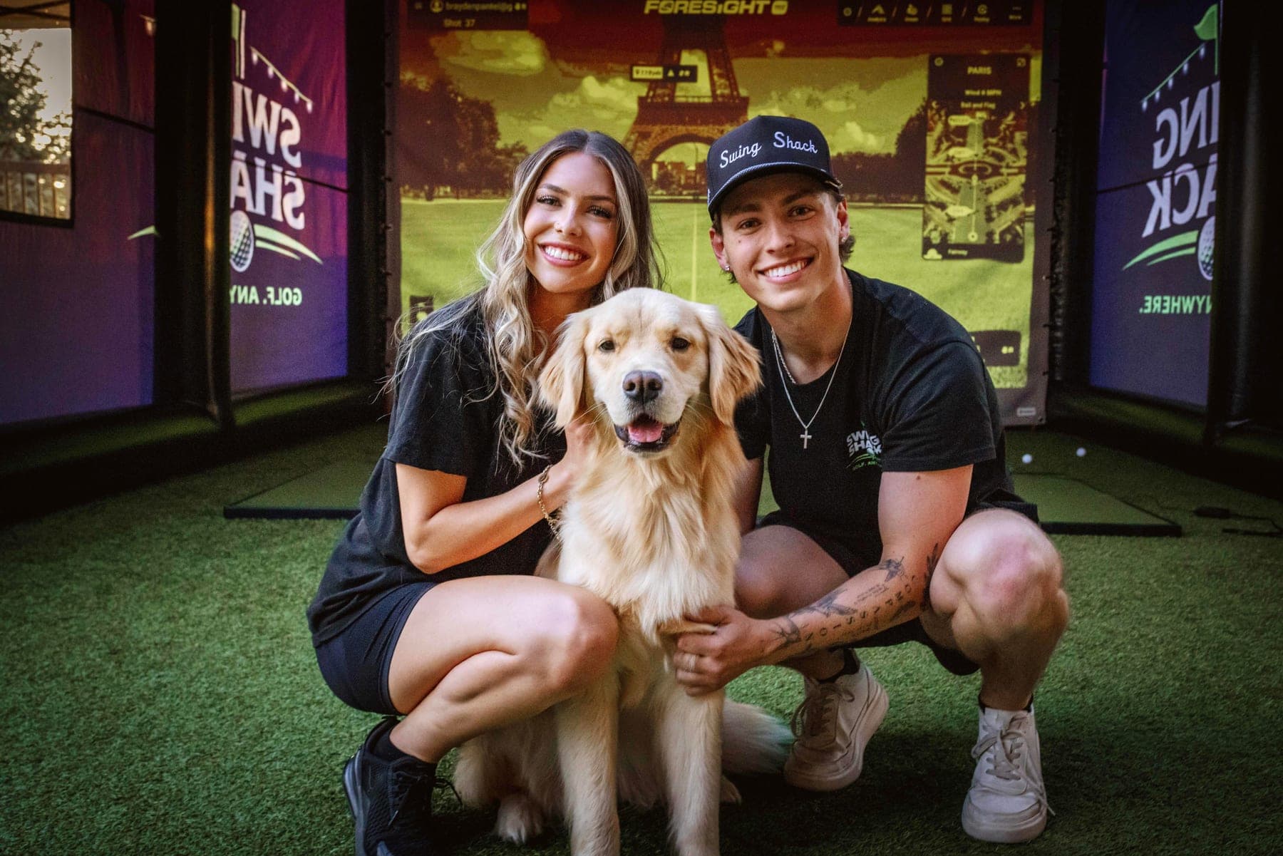 The Swing Shack owners crouching with their golden retriever inside the simulator enclosure