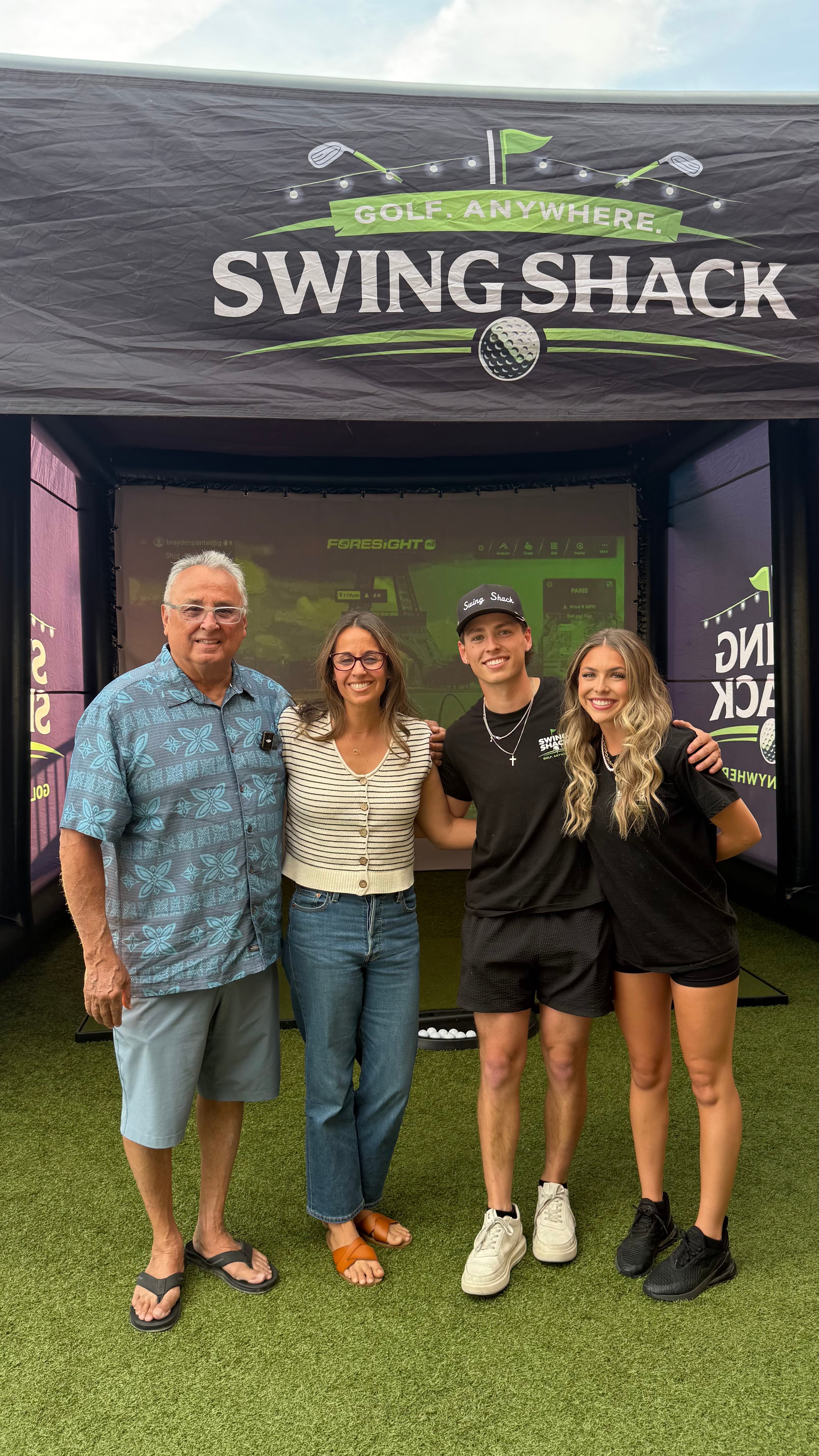 Family posing together in front of the Swing Shack simulator