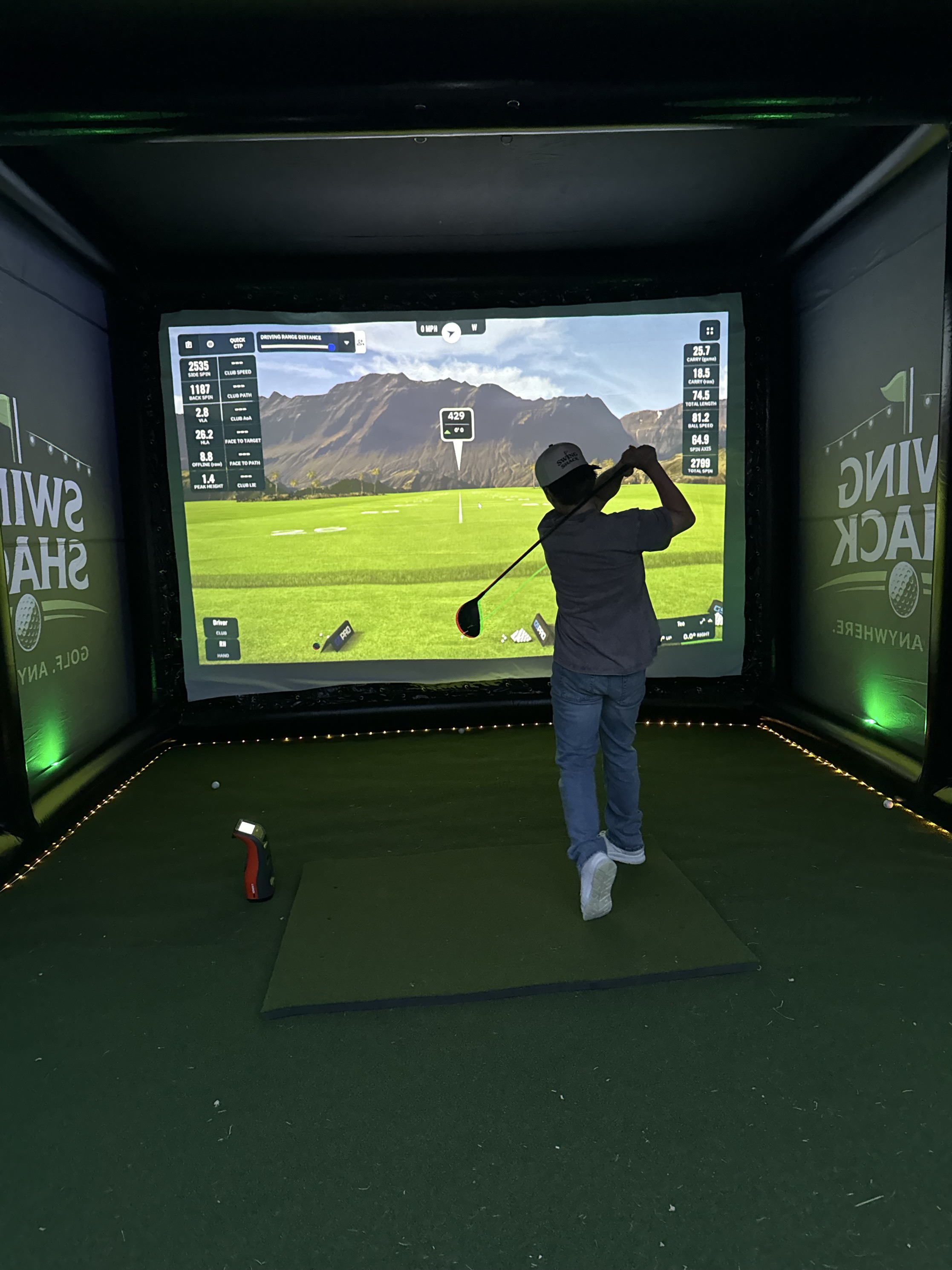 Golfer taking a swing in the simulator under the lights at night